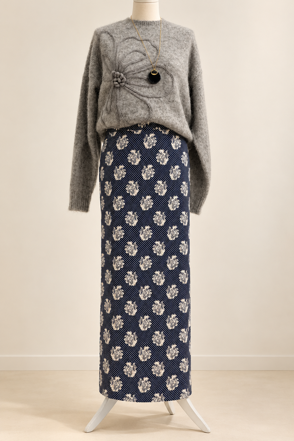 Gonna lunga blu con stampa chiara, abbinata a un maglione grigio sul manichino. Il prezzo si riferisce alla gonna.